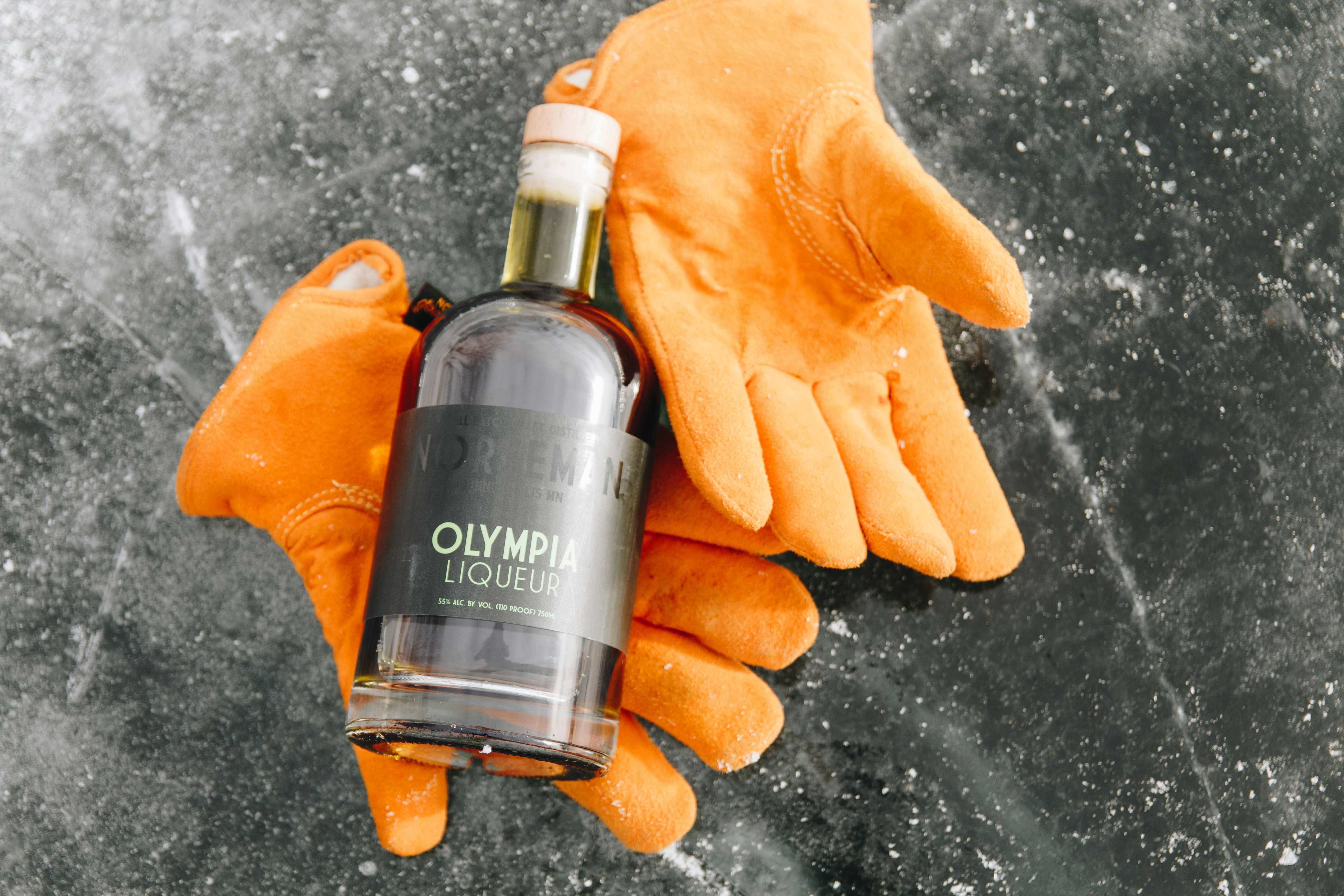 A pair of orange gloves holding a bottle of alcohol