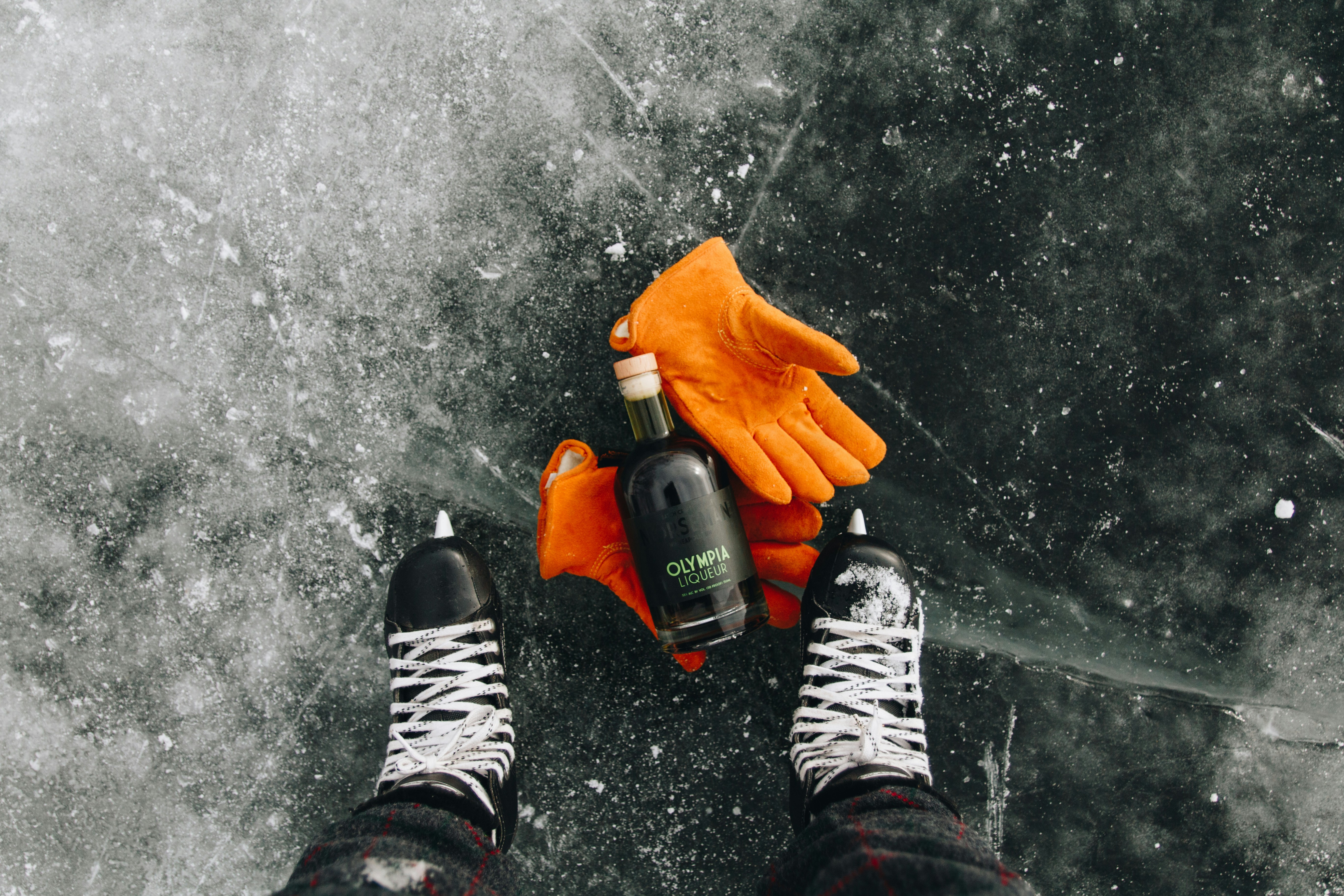 A pair of feet wearing orange gloves and holding a bottle of water
