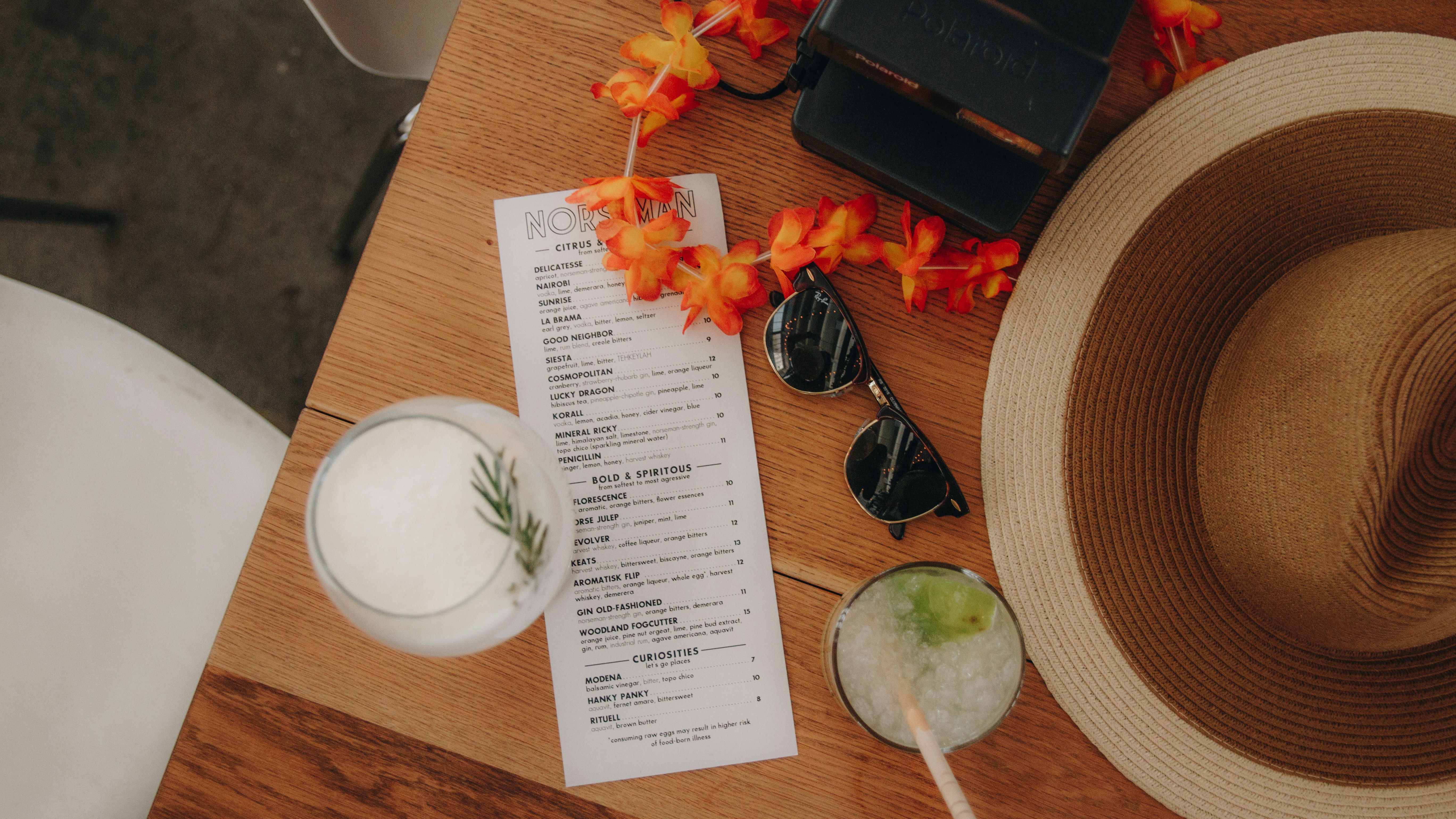 A wooden table topped with a hat and a menu