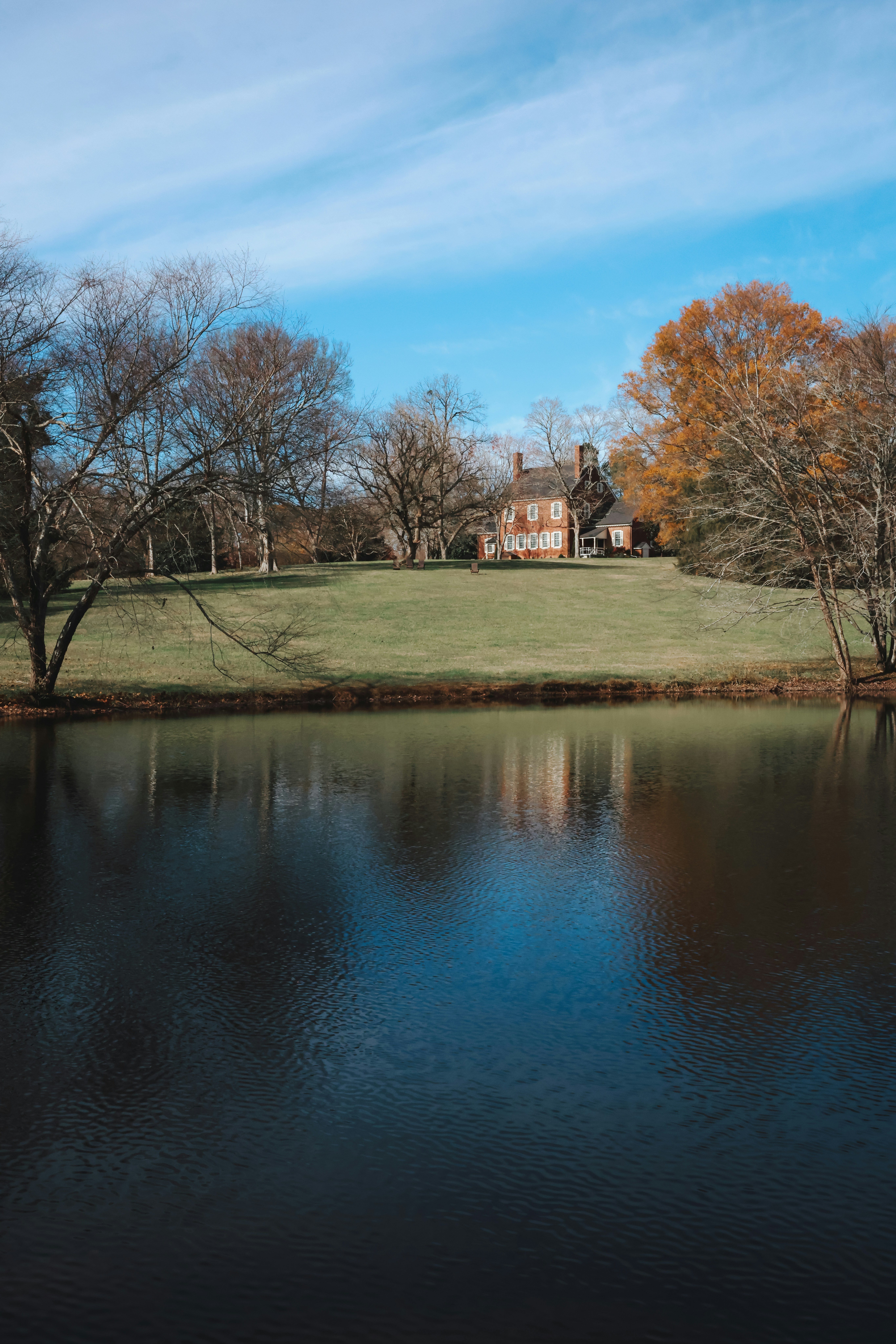Ein See mit einem Haus auf einem Hügel im Hintergrund