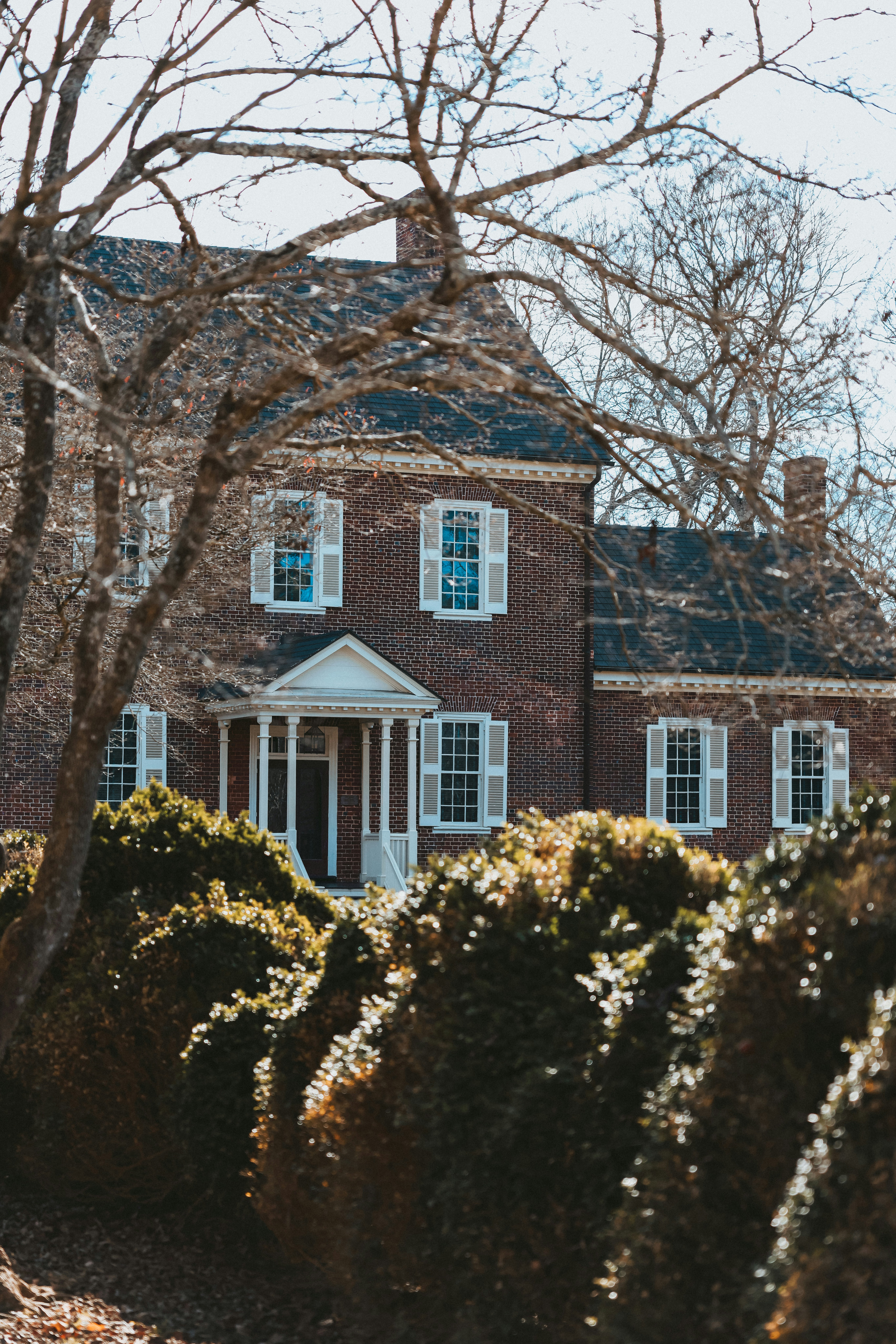 Ein großes Backsteinhaus, umgeben von Bäumen und Sträuchern