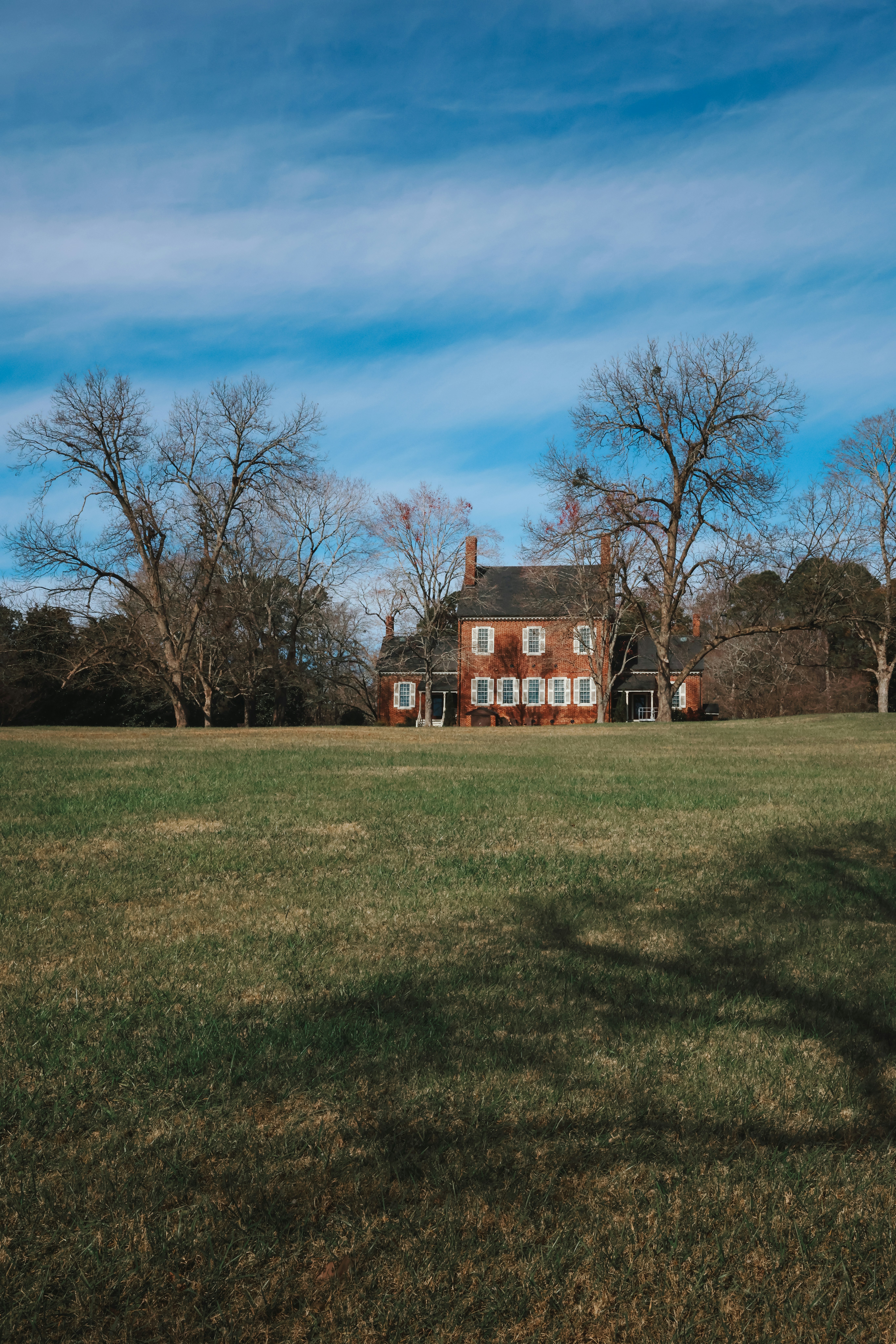 Ein großes braunes Haus, das auf einer saftig grünen Wiese thront