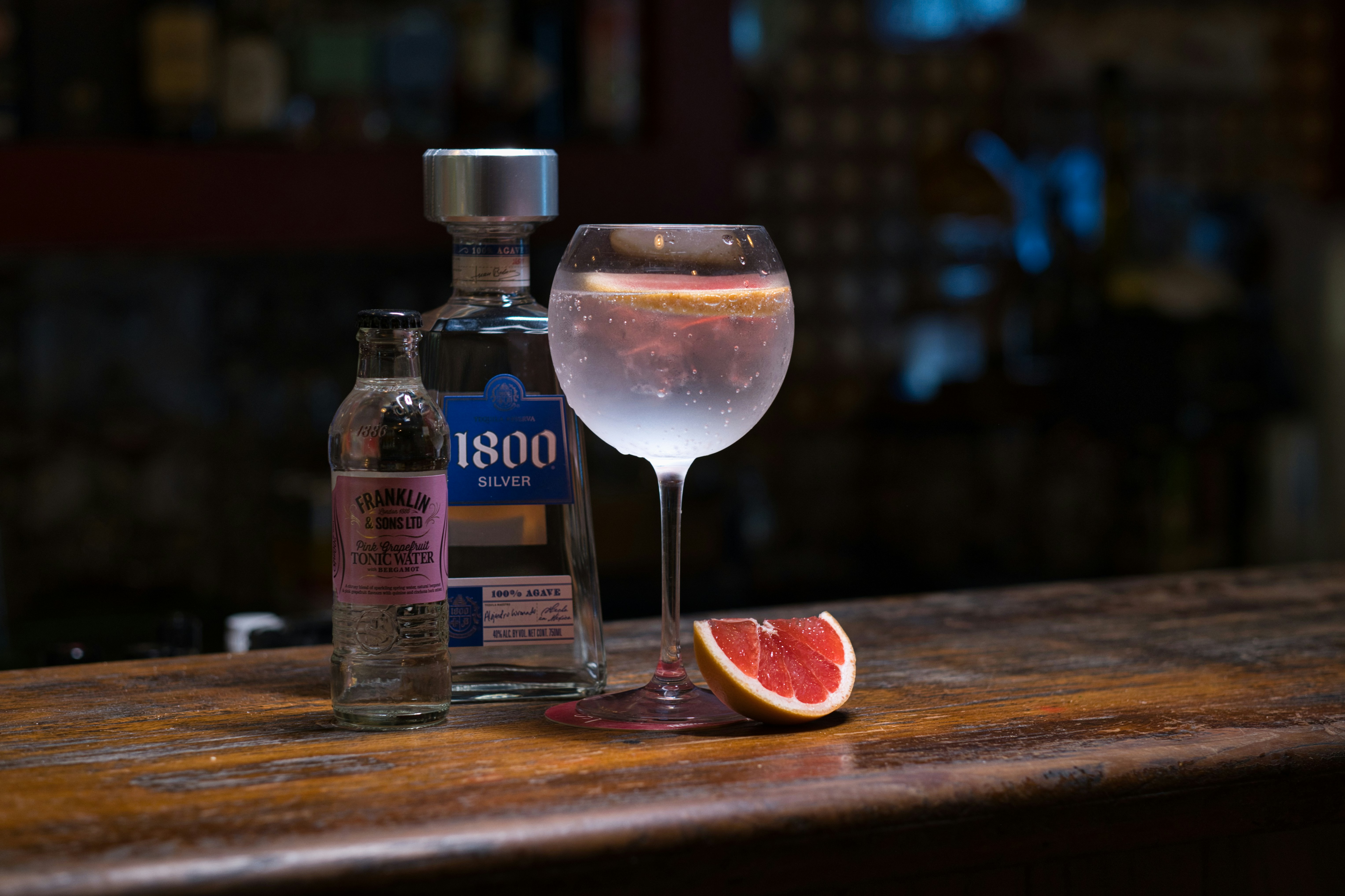 A bottle of alcohol and a glass of wine on a table