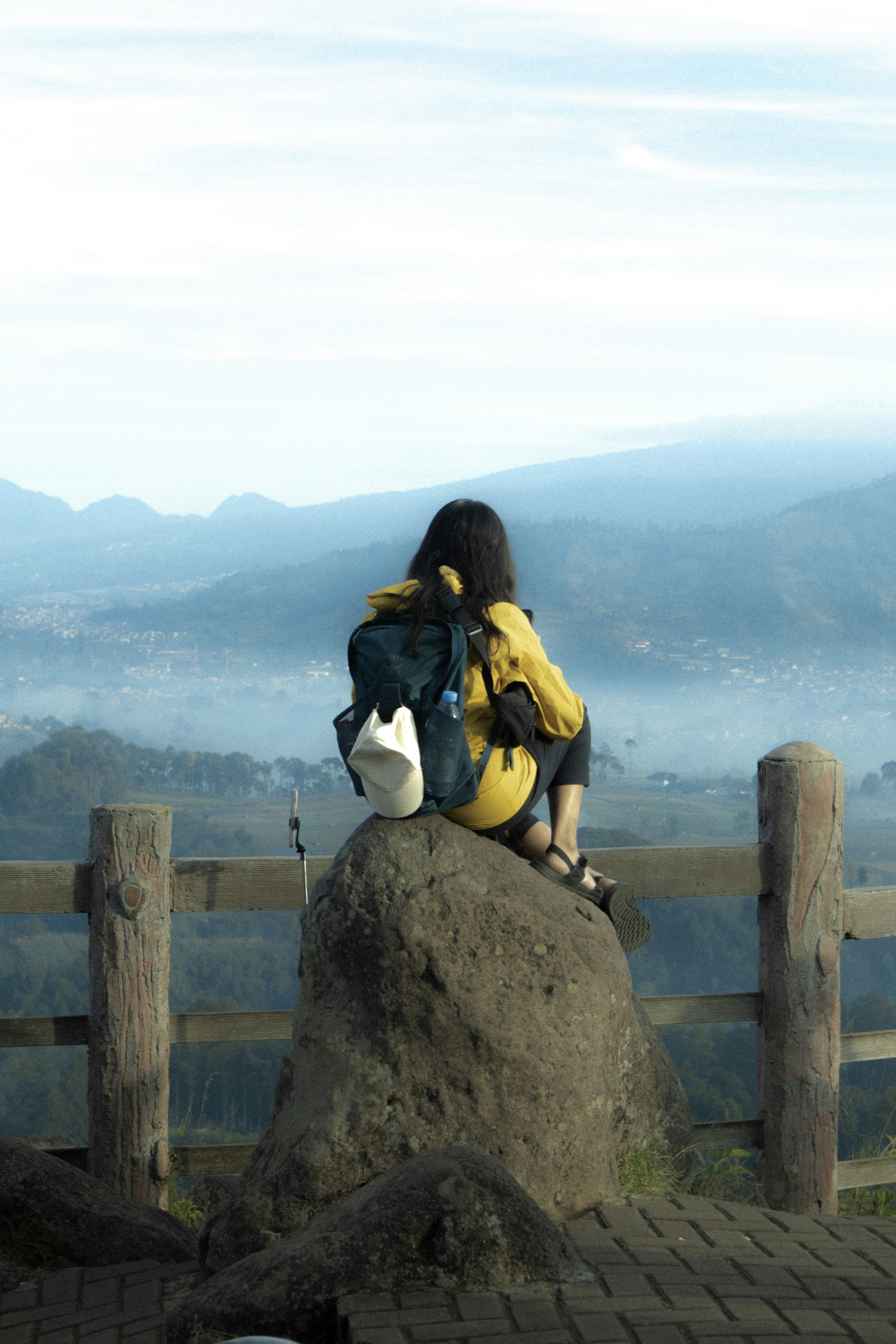 A woman sitting on top of a large rock
