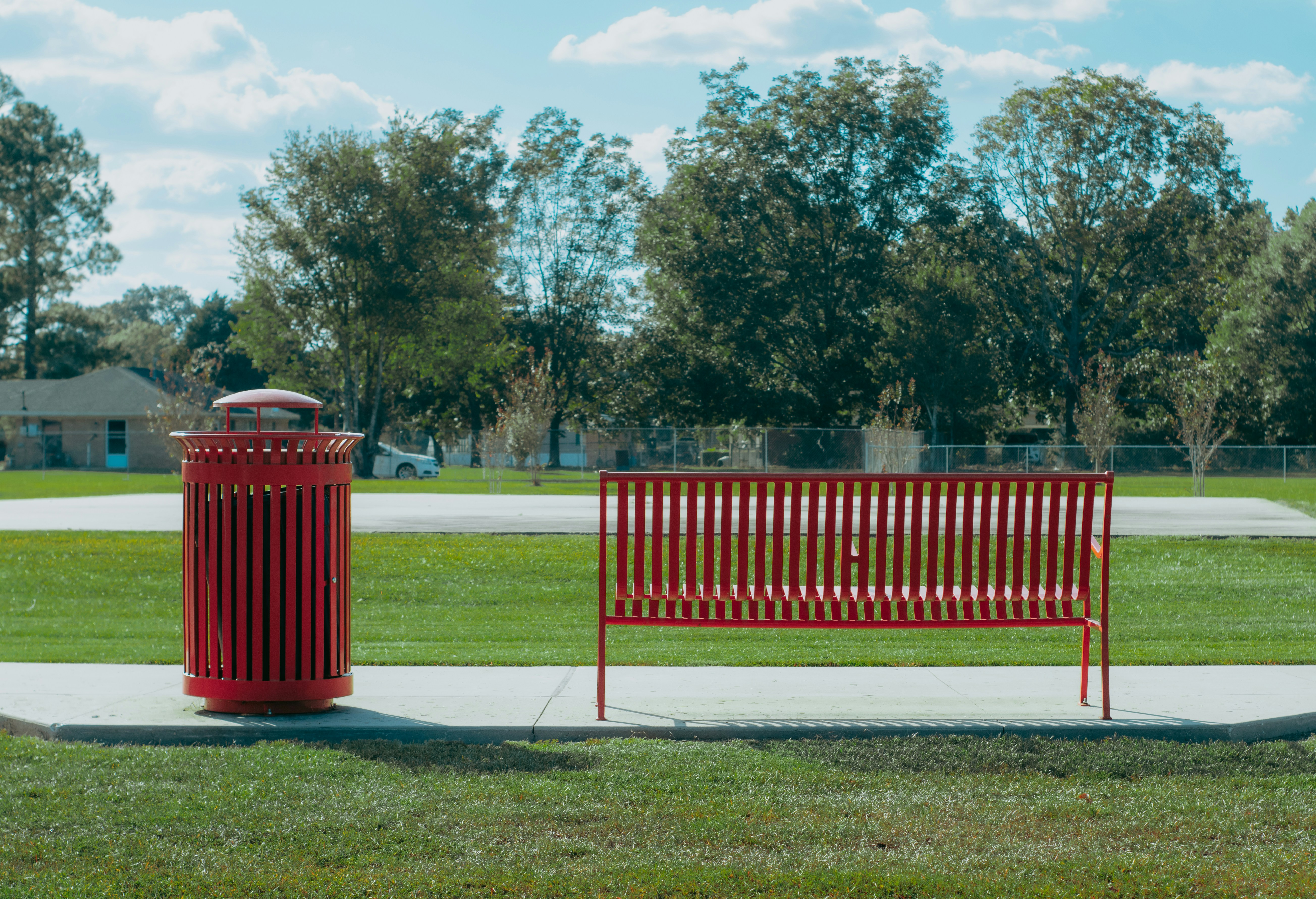 A red bench sitting next to a red trash can