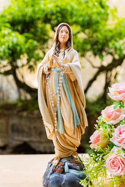 A statue of the virgin mary holding a rosary