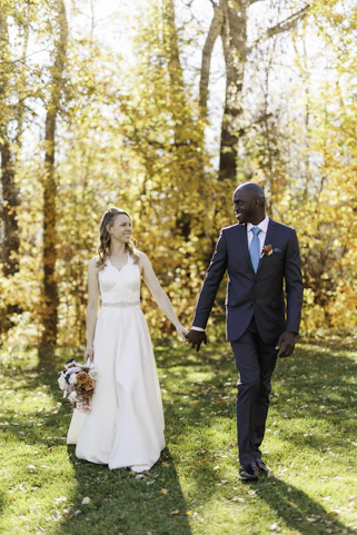 A bride and groom holding hands in the woods