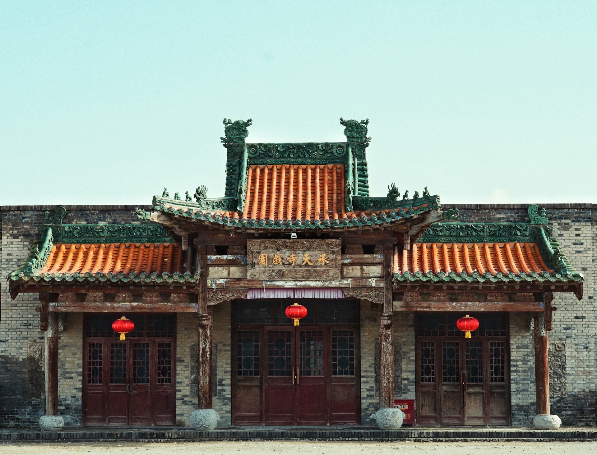 A chinese building with red lanterns hanging from it's roof