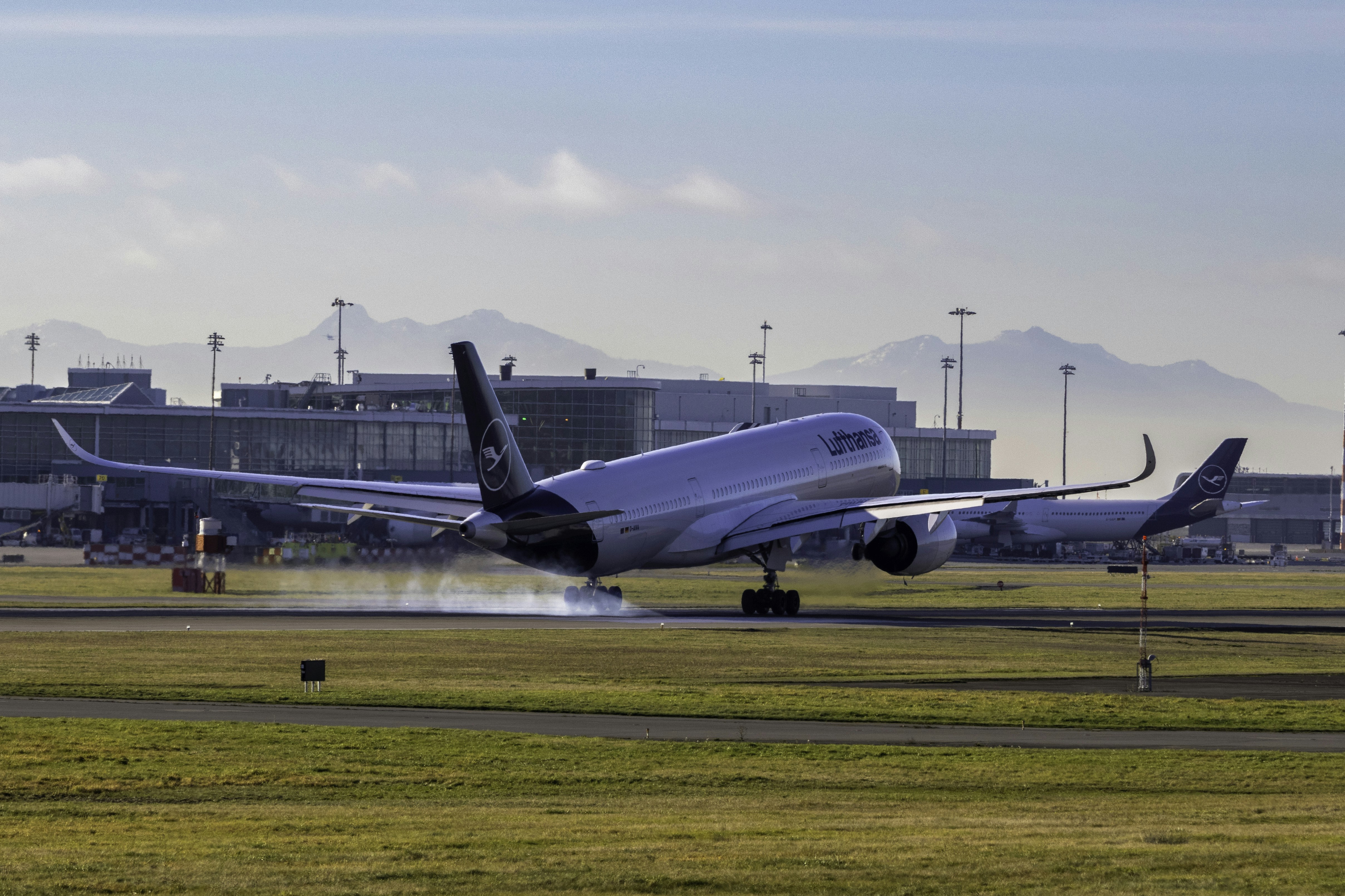 A large jetliner taking off from an airport runway, Lufthansa Airbus A350-900 landing at YVR - Vancouver Airport on a bright sunny day.