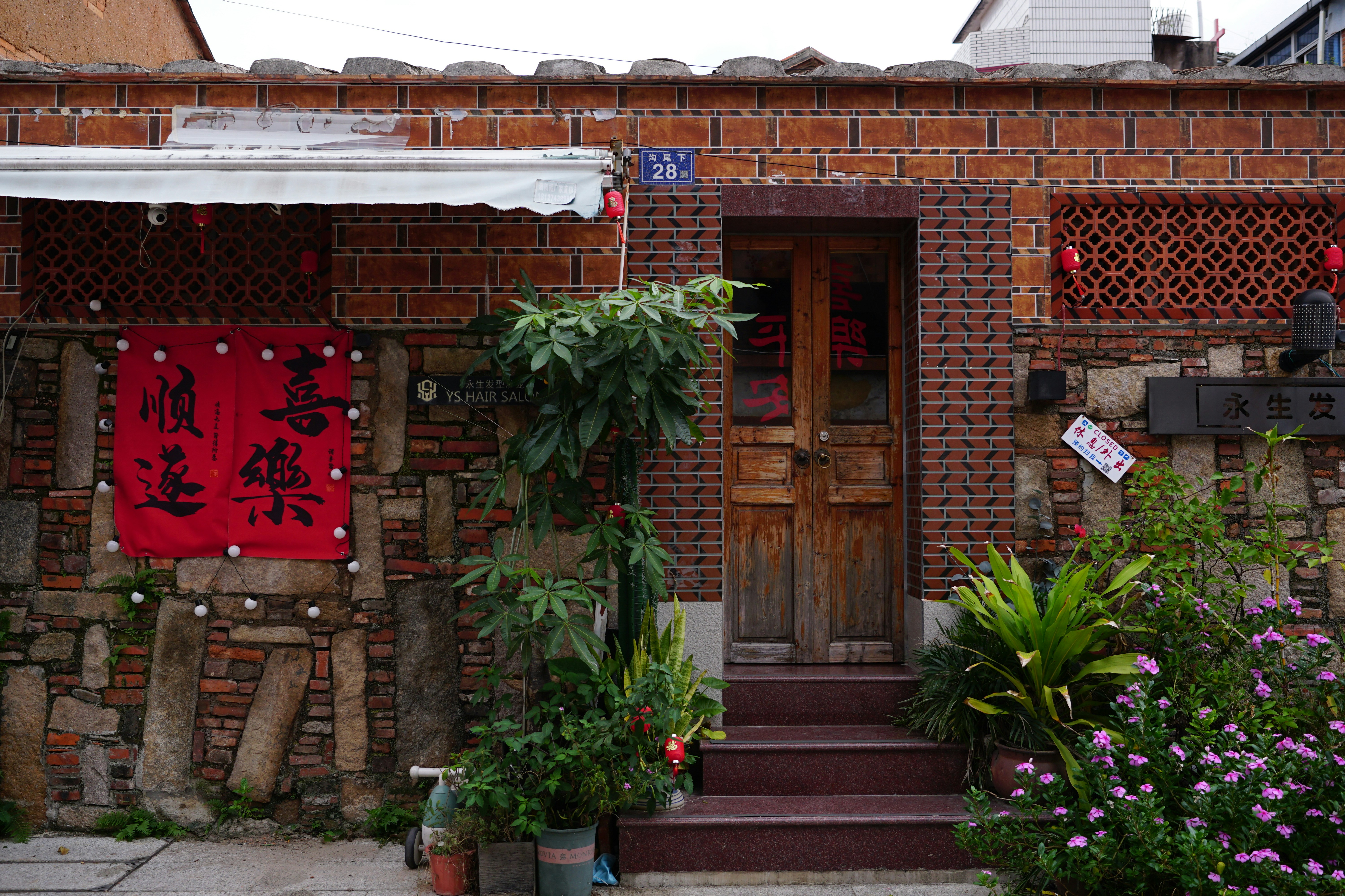 A brick building with a red door and steps leading up to it
