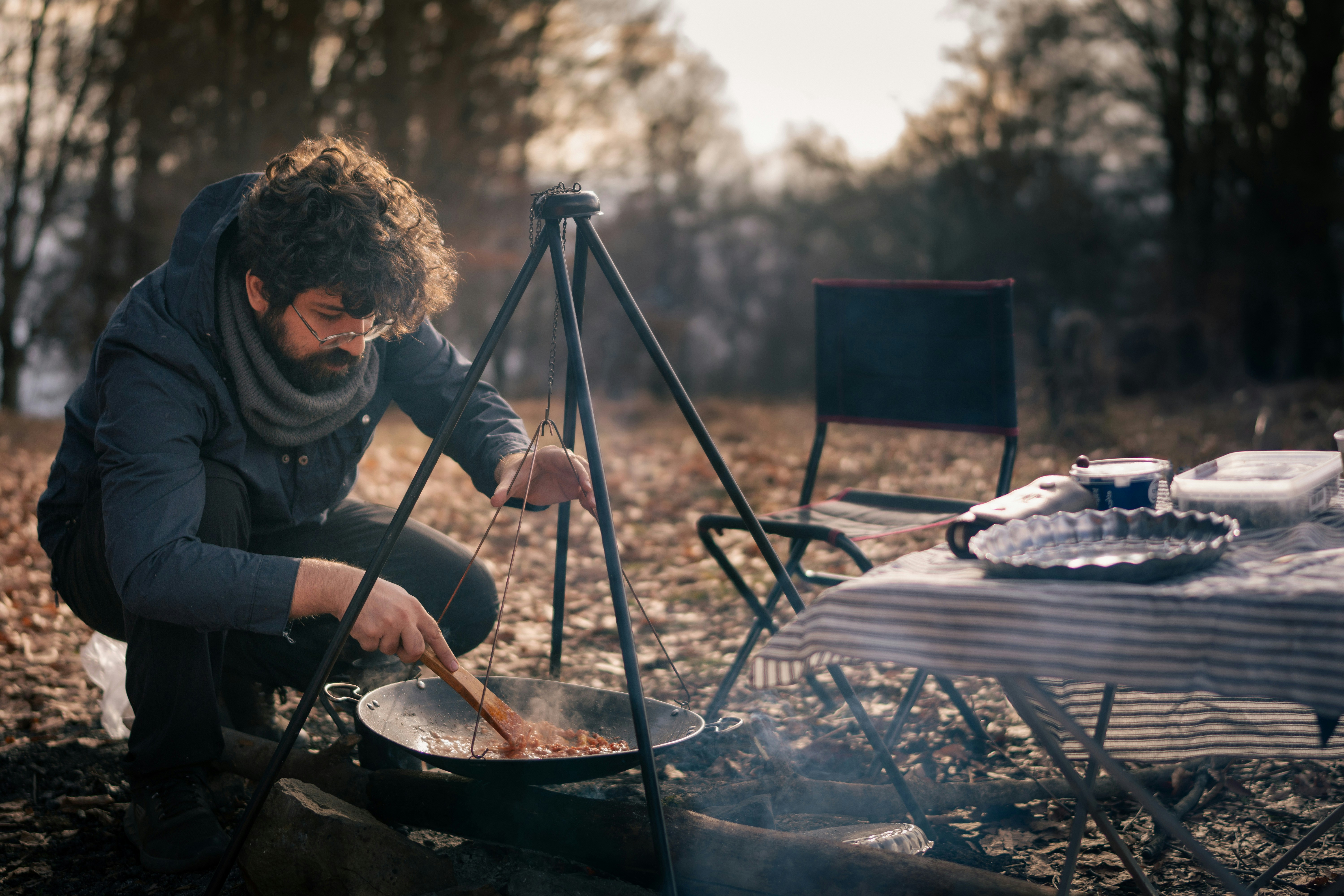 A man cooking on a grill in the woods