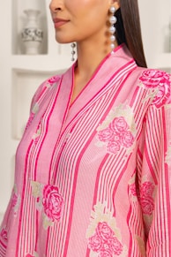 A woman wearing a pink and white shirt and earrings
