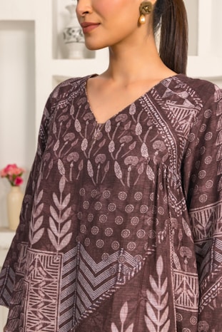 A woman standing in a kitchen wearing a brown top