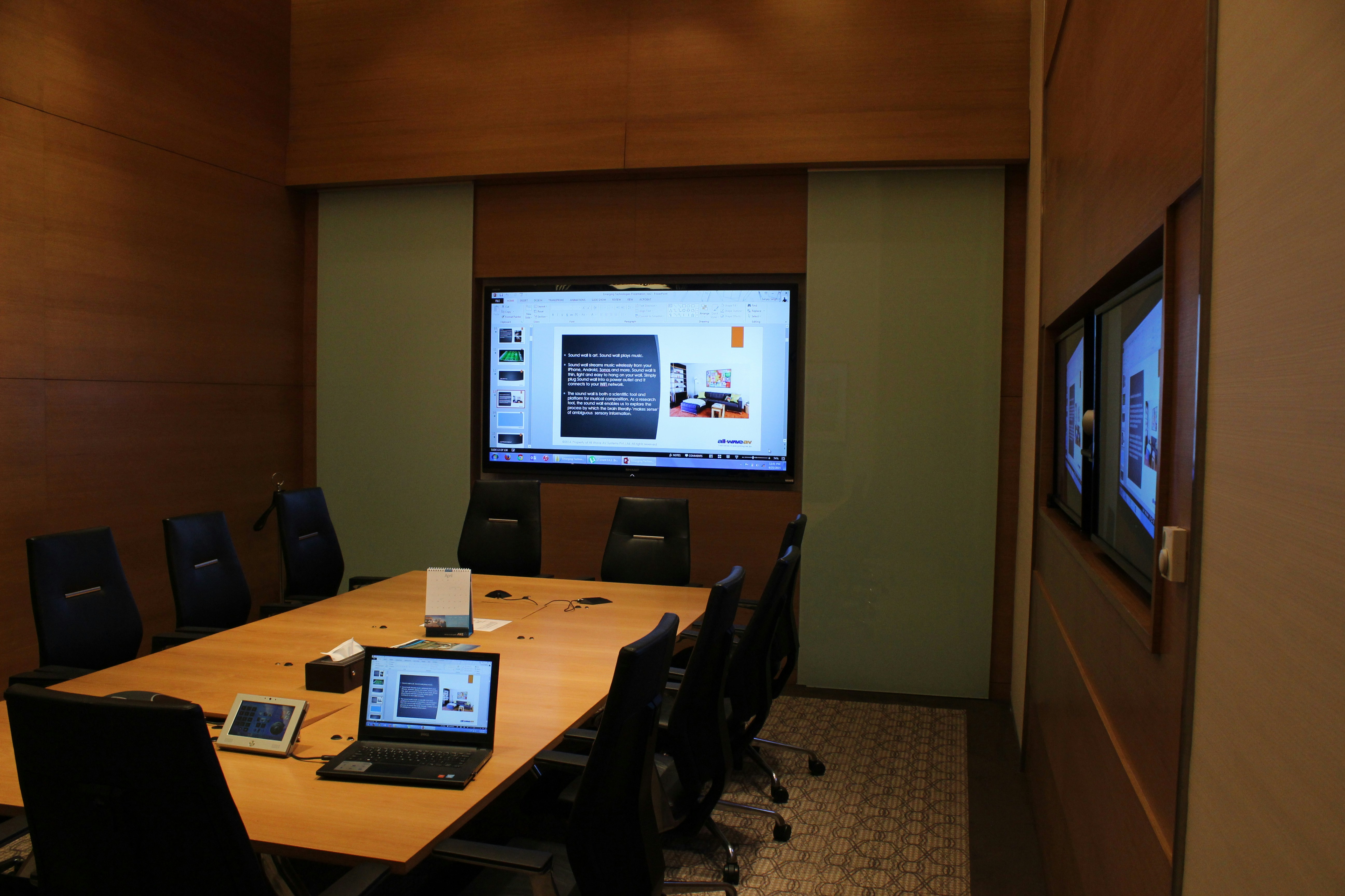Training presentation slides displayed on screen in modern conference room with materials on table
