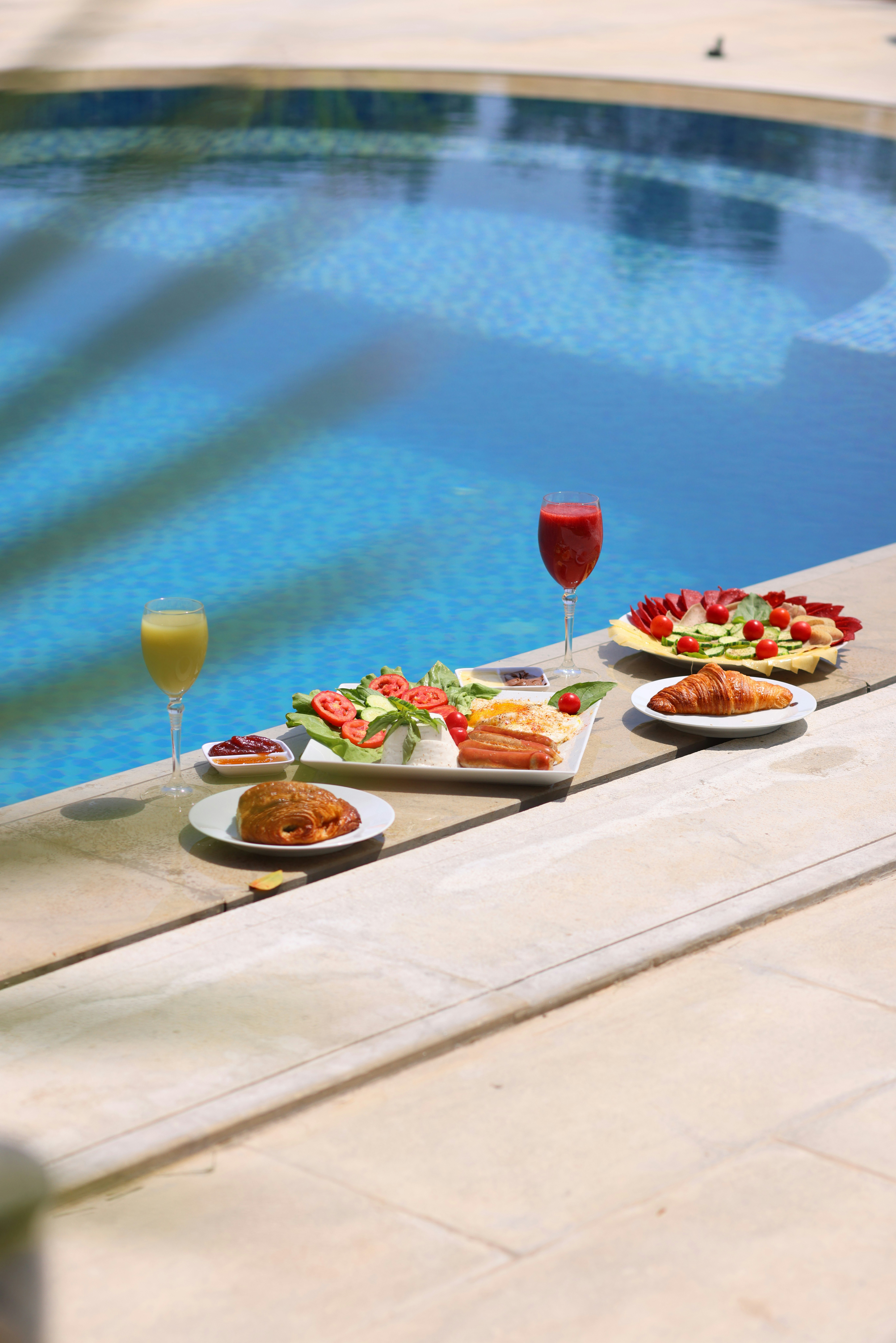 A table with plates of food next to a swimming pool