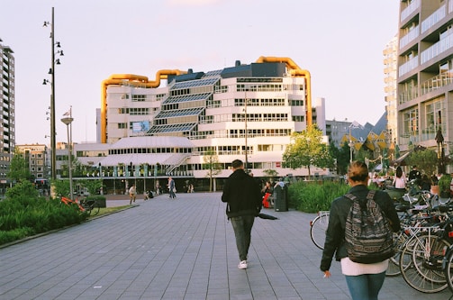 A couple of people walking down a street next to tall buildings