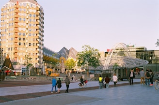 A group of people walking down a street next to tall buildings