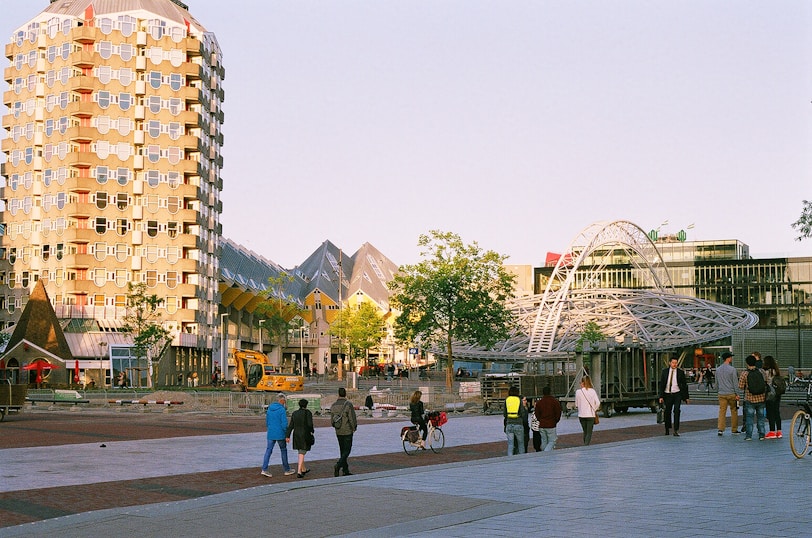A group of people walking down a street next to tall buildings