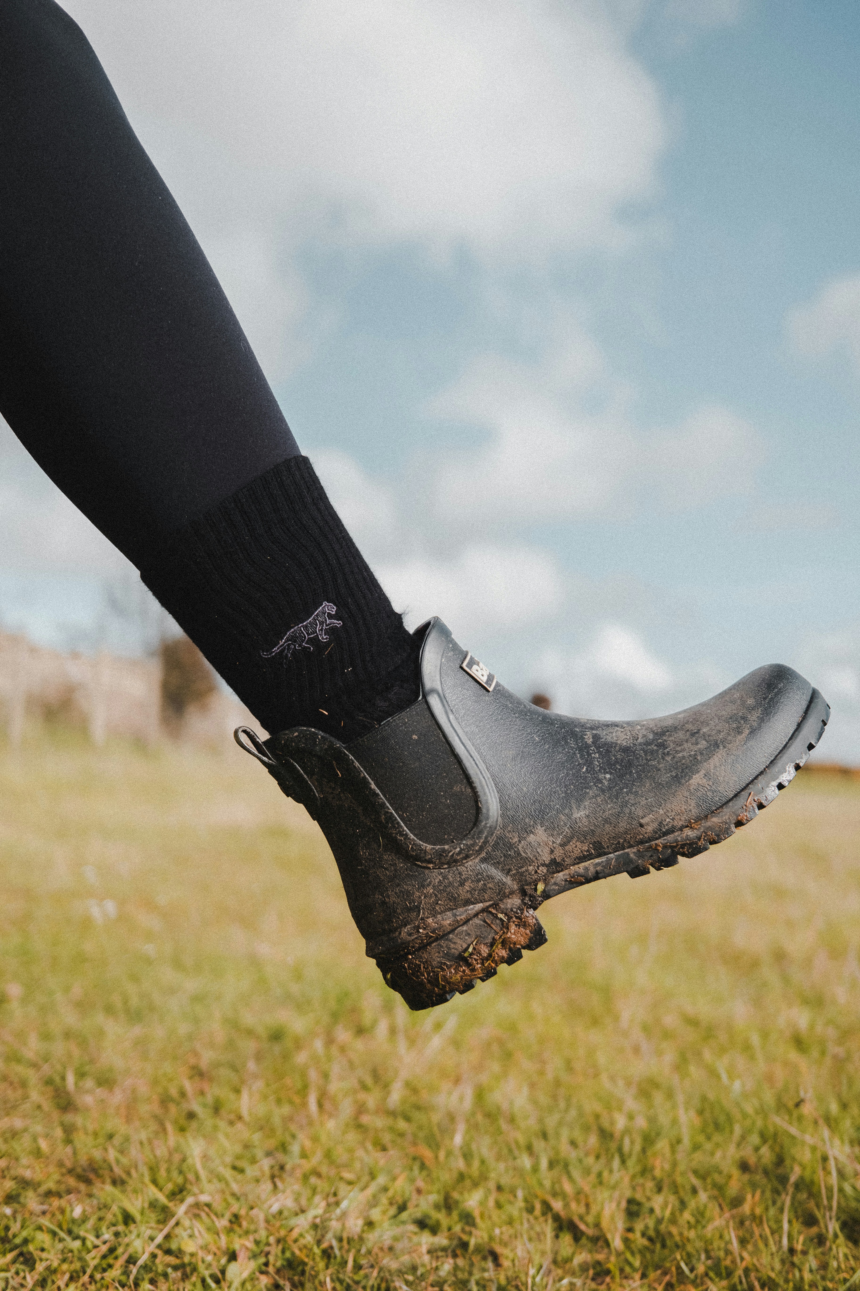 A person standing in a field wearing black boots
