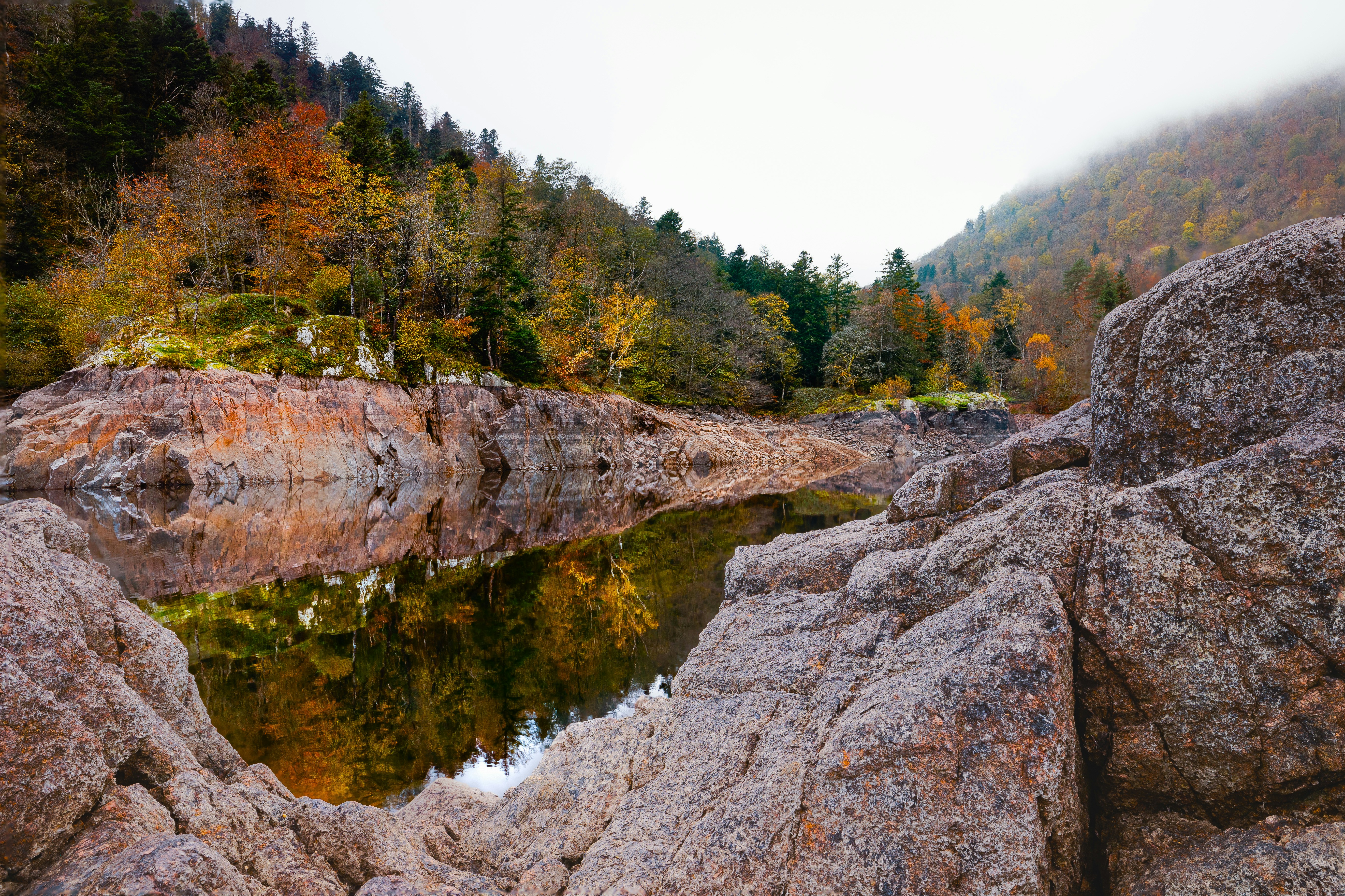 A lake surrounded by large rocks in the middle of a forest