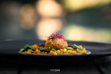 A black plate topped with food on top of a wooden table