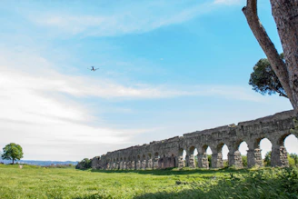 A large stone bridge over a lush green field