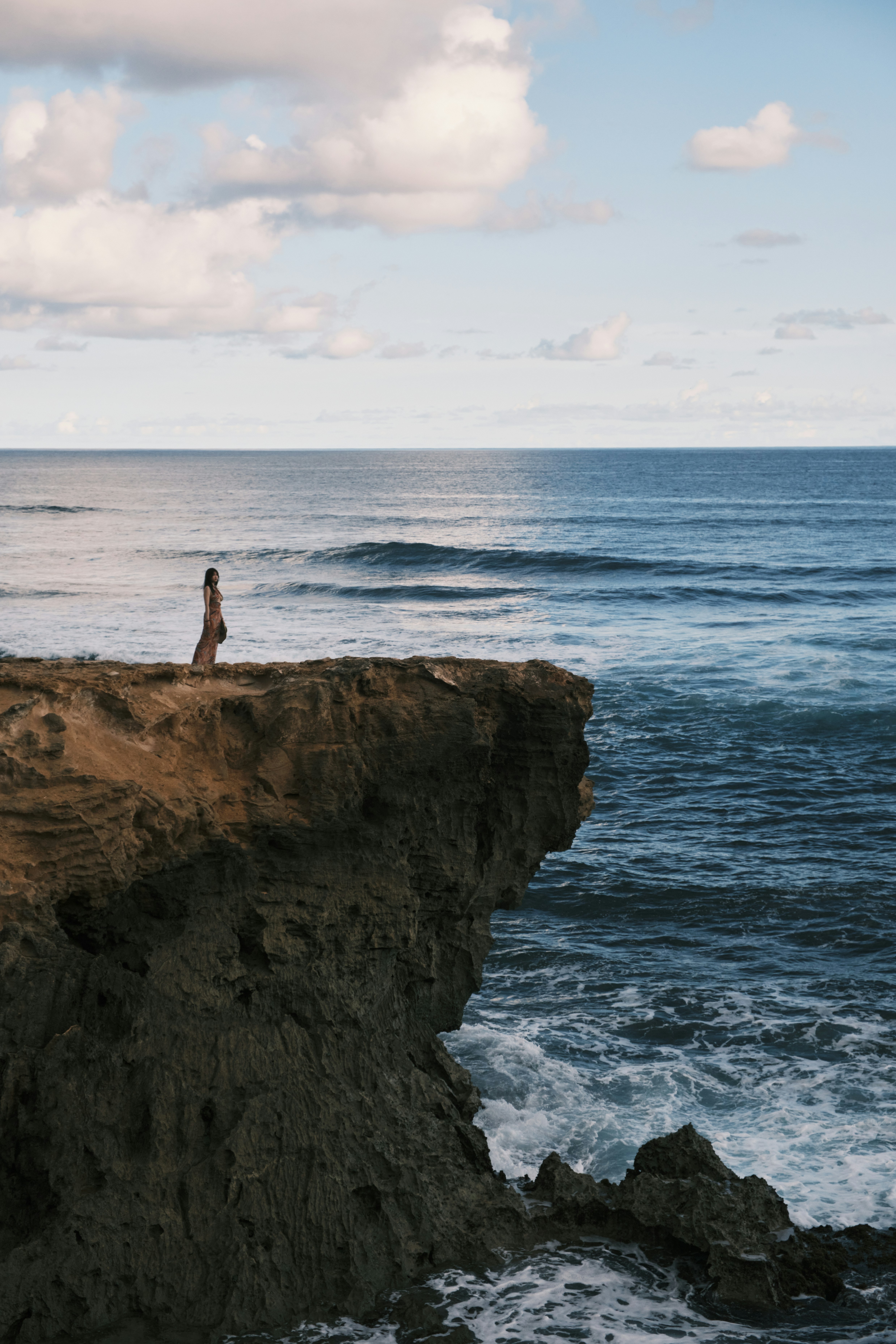A person standing on a cliff overlooking the ocean