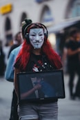 A woman with a laptop wearing a clown mask