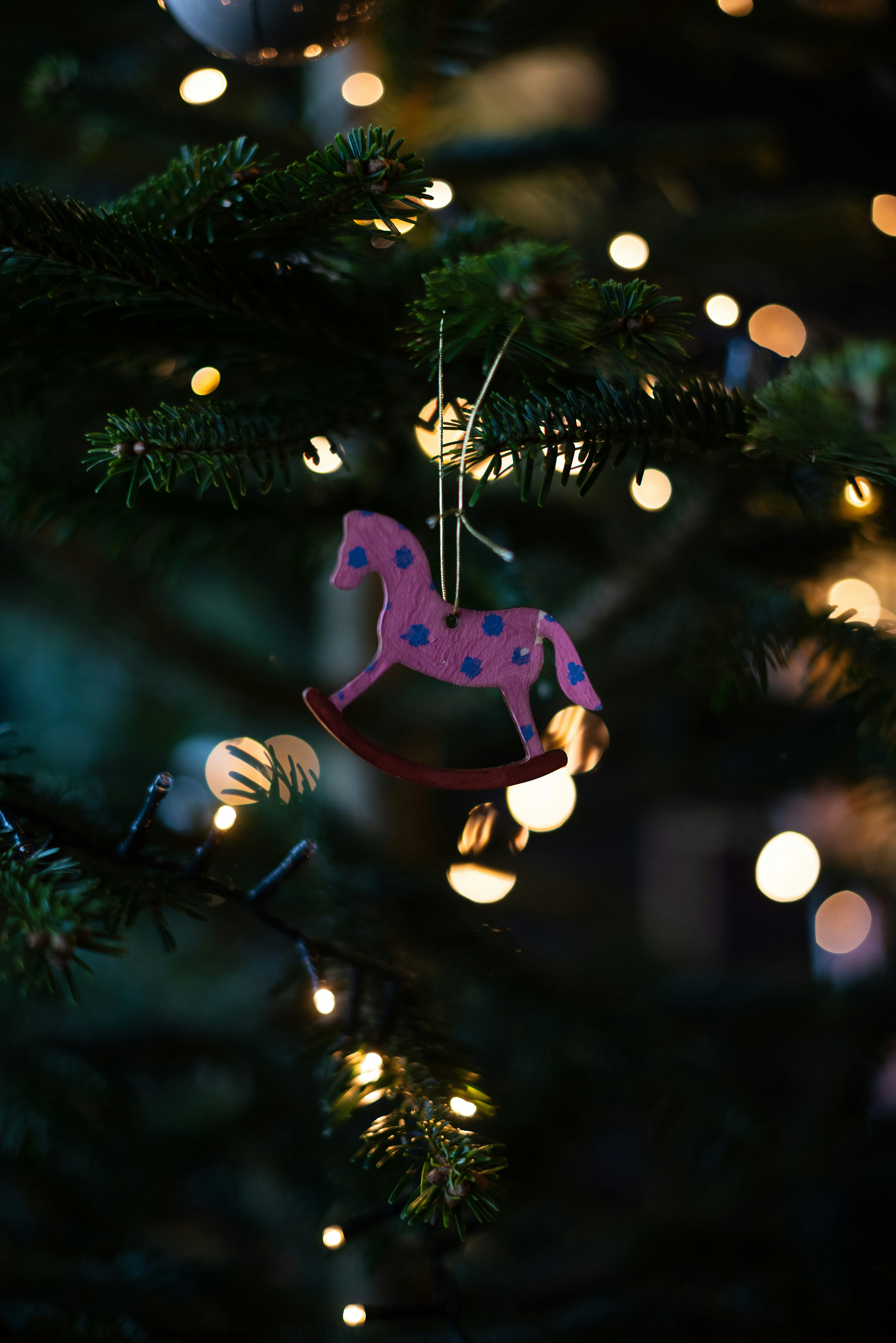 A pink horse ornament hanging from a christmas tree
