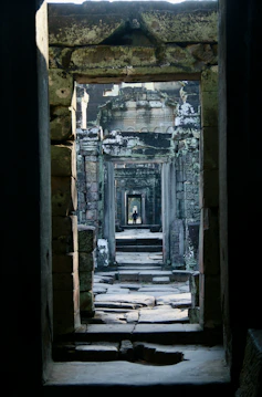 A doorway in a stone building with a cat laying on the floor