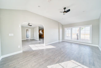 An empty living room with a ceiling fan
