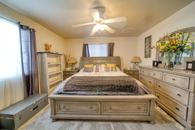 A bedroom with a bed, dressers and a mirror