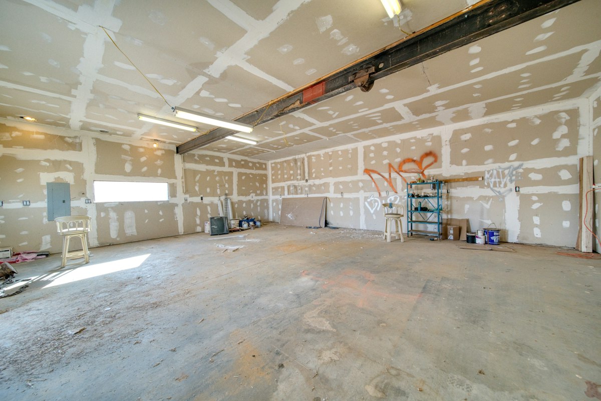 An empty room with taped and mudded drywall sheets on the walls and ceiling