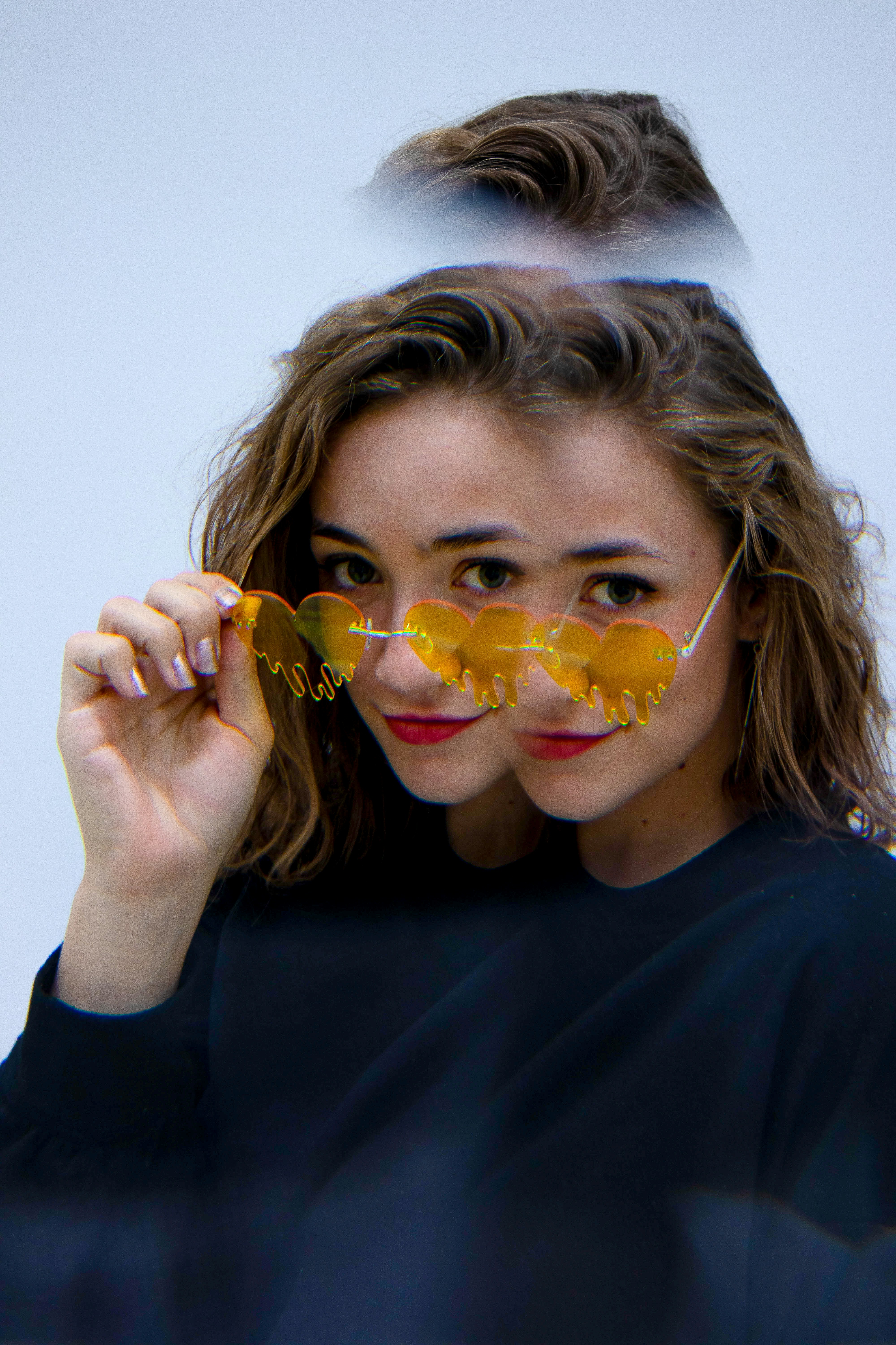 A woman wearing yellow sunglasses looking at the camera