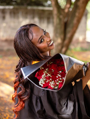 A woman in a graduation gown holding a bouquet of flowers