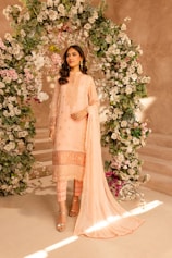 A woman standing in front of a floral arch