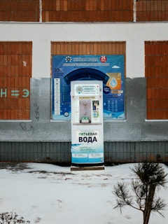 A snow covered street with a vending machine in front of a building
