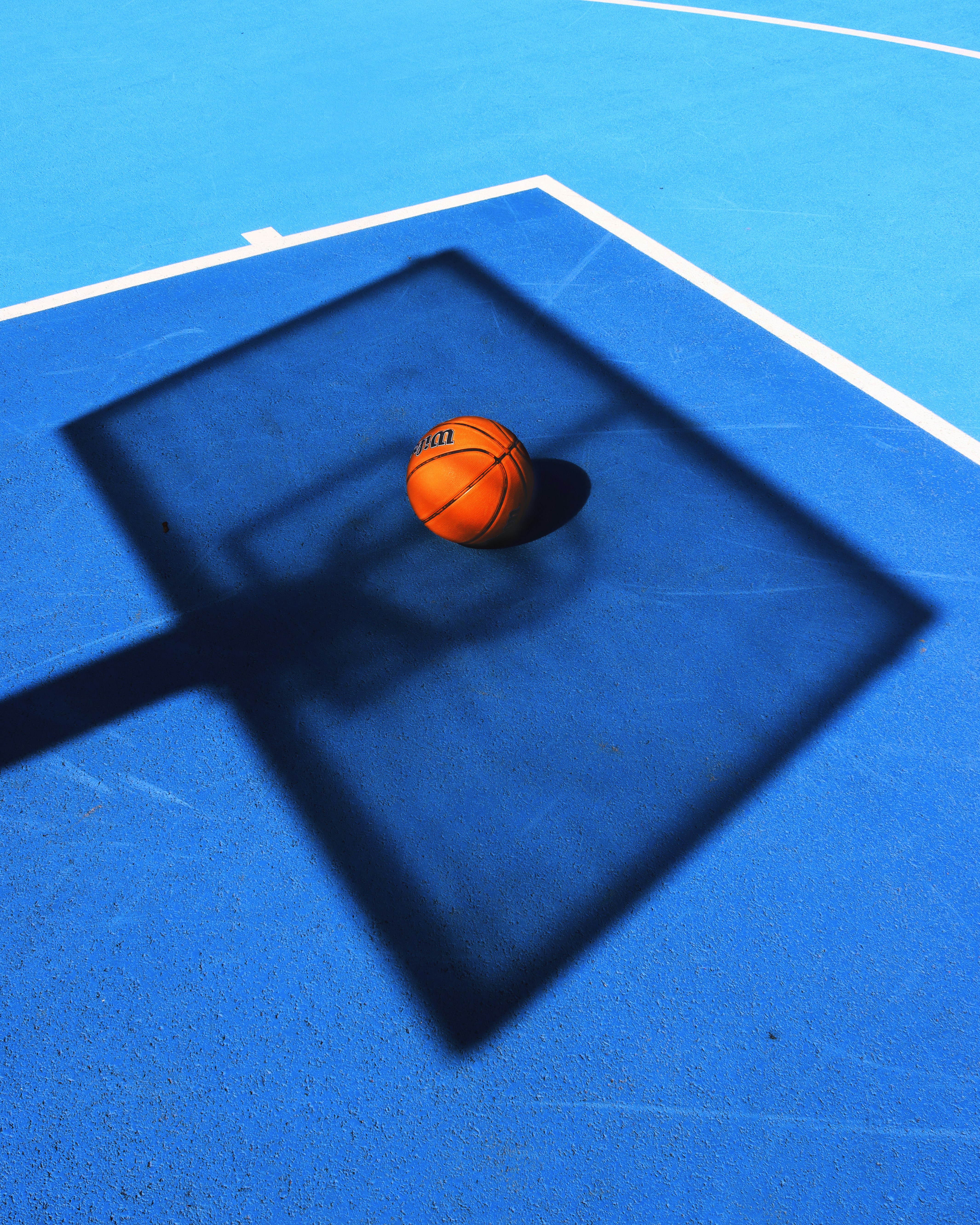 L’ombre d’un ballon de basket sur un terrain bleu