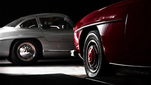 A red car and a silver car in a dark room