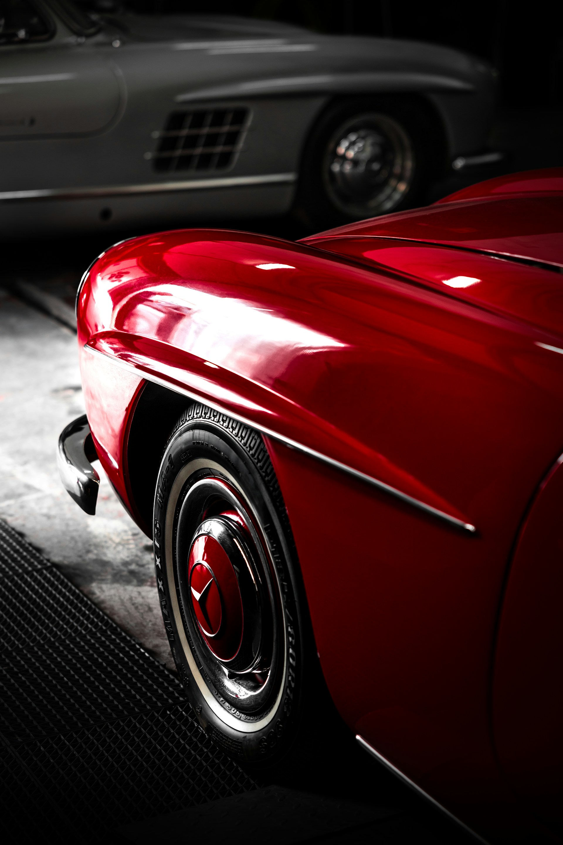 A red car parked in a garage next to another car