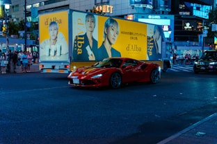 A red sports car driving down a city street