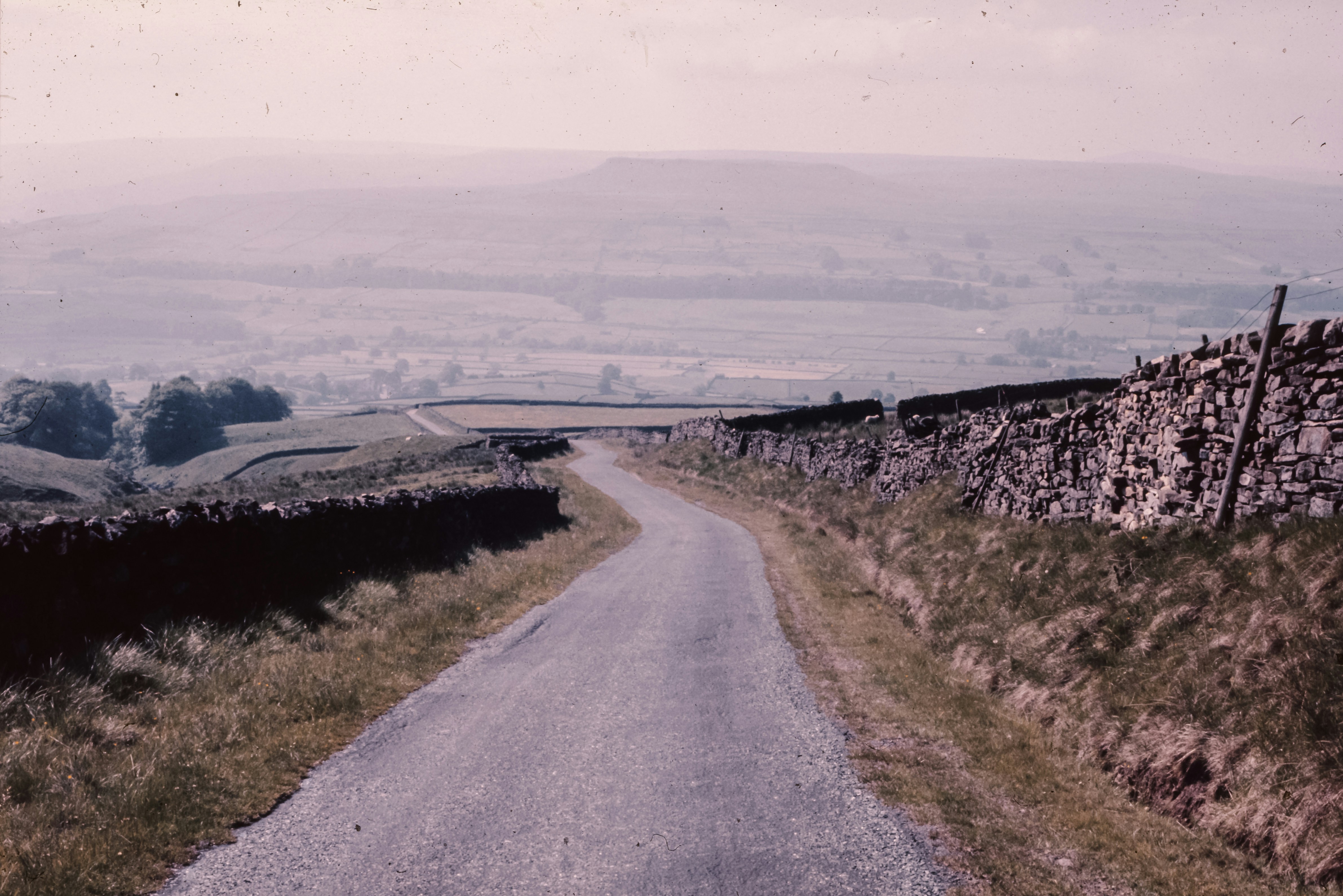 Uma estrada de terra com um muro de pedra ao lado