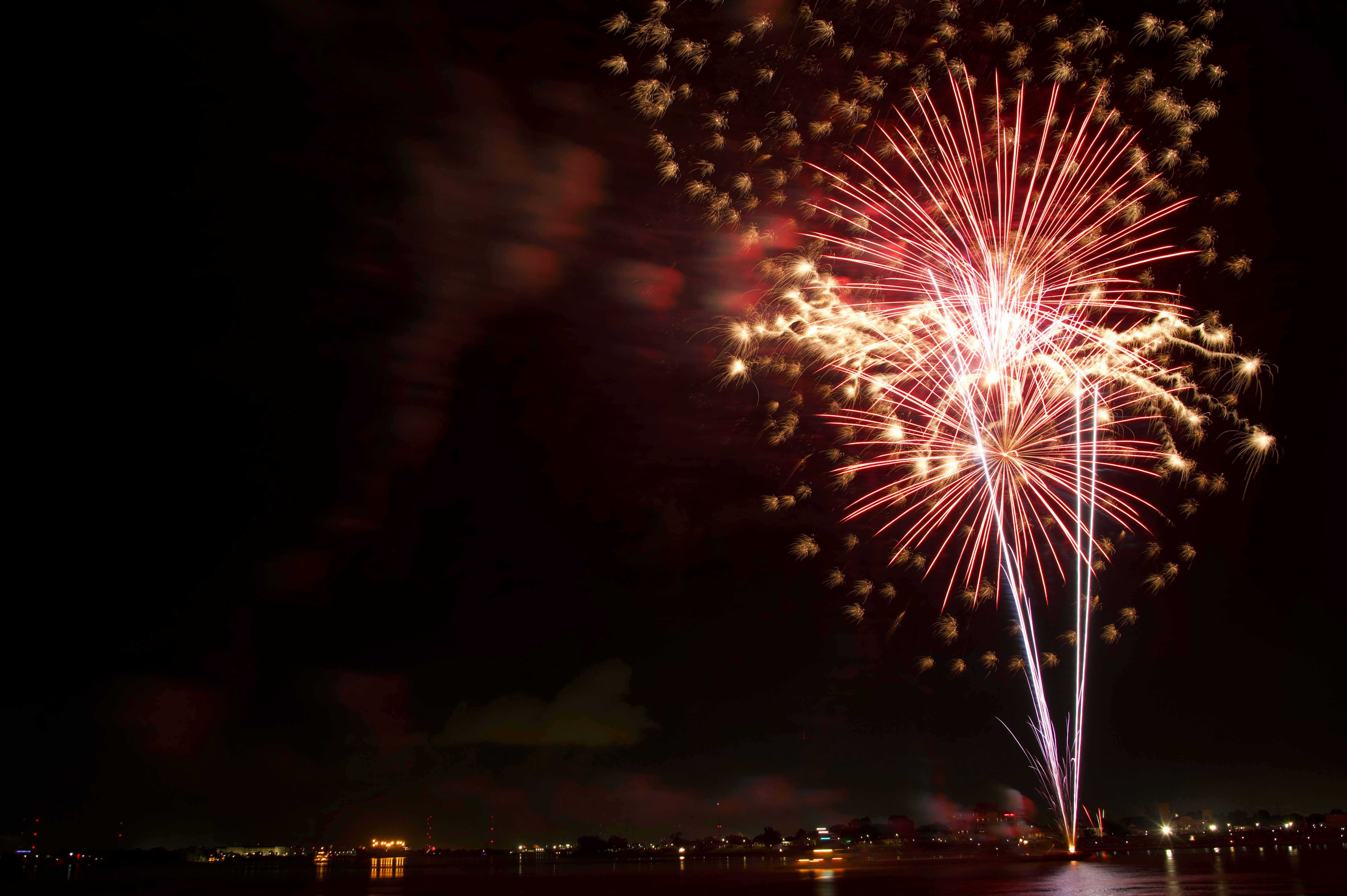 A firework display in the night sky over a body of water