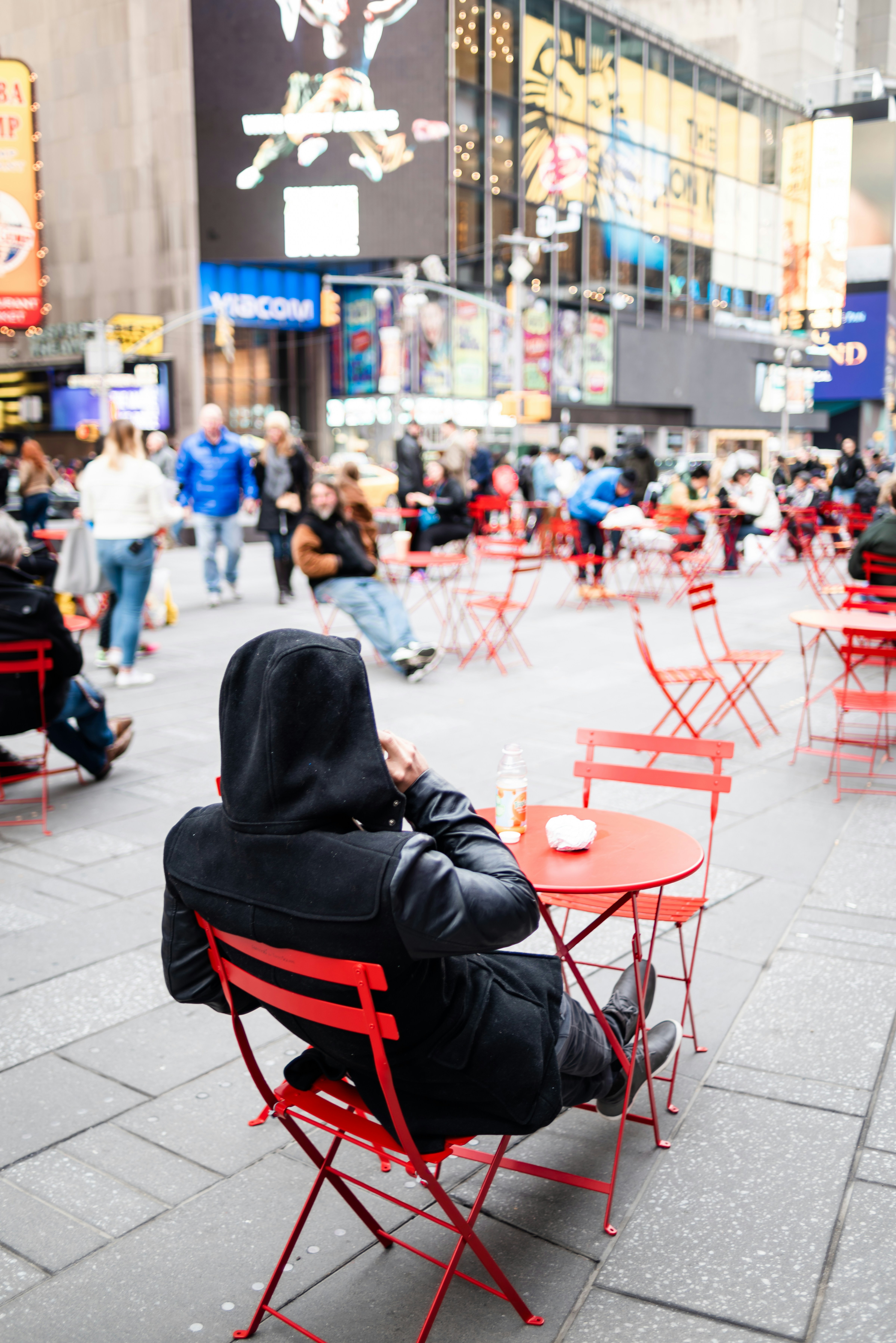 A person sitting on a red chair in the middle of a street