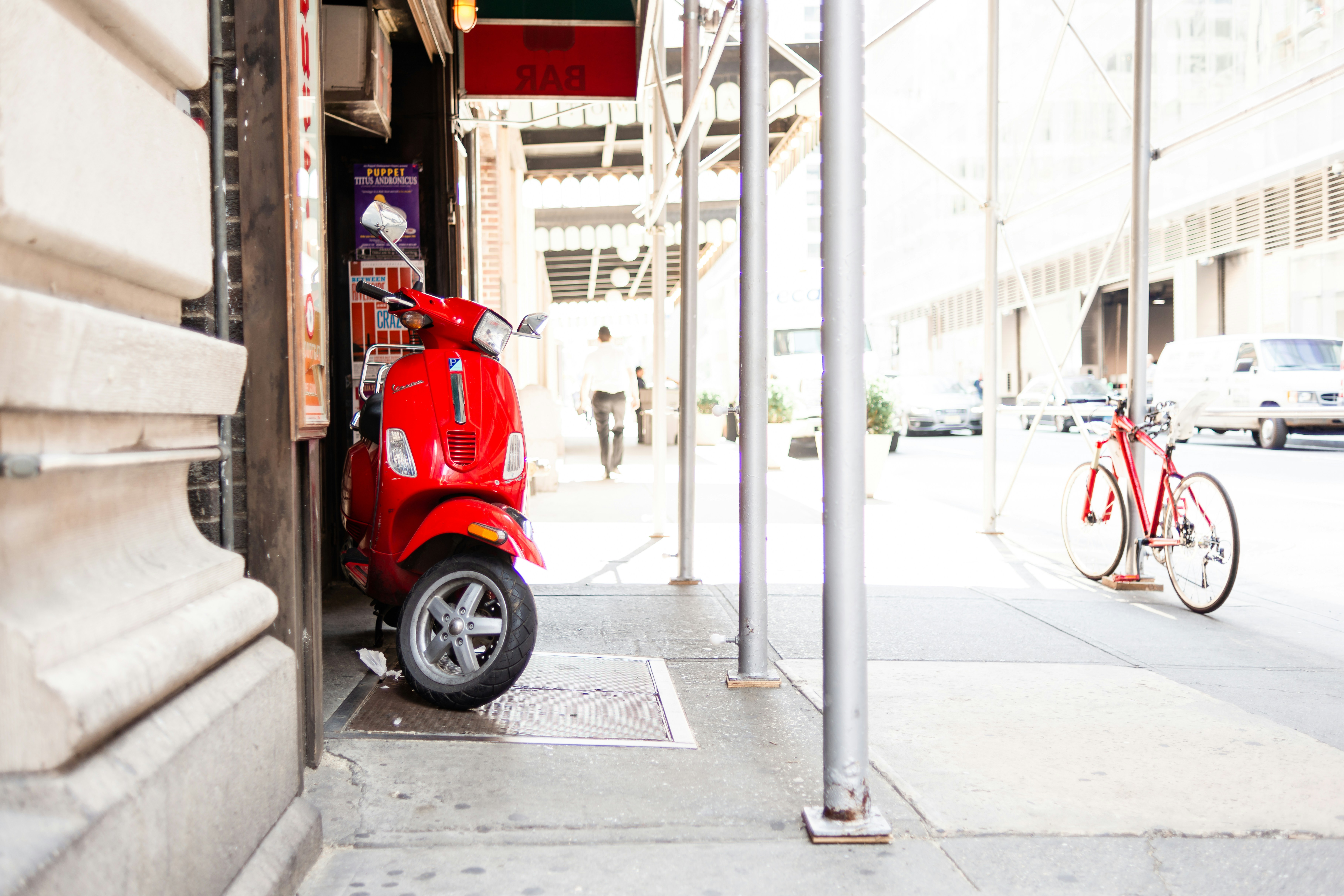 A red scooter parked on the side of a building