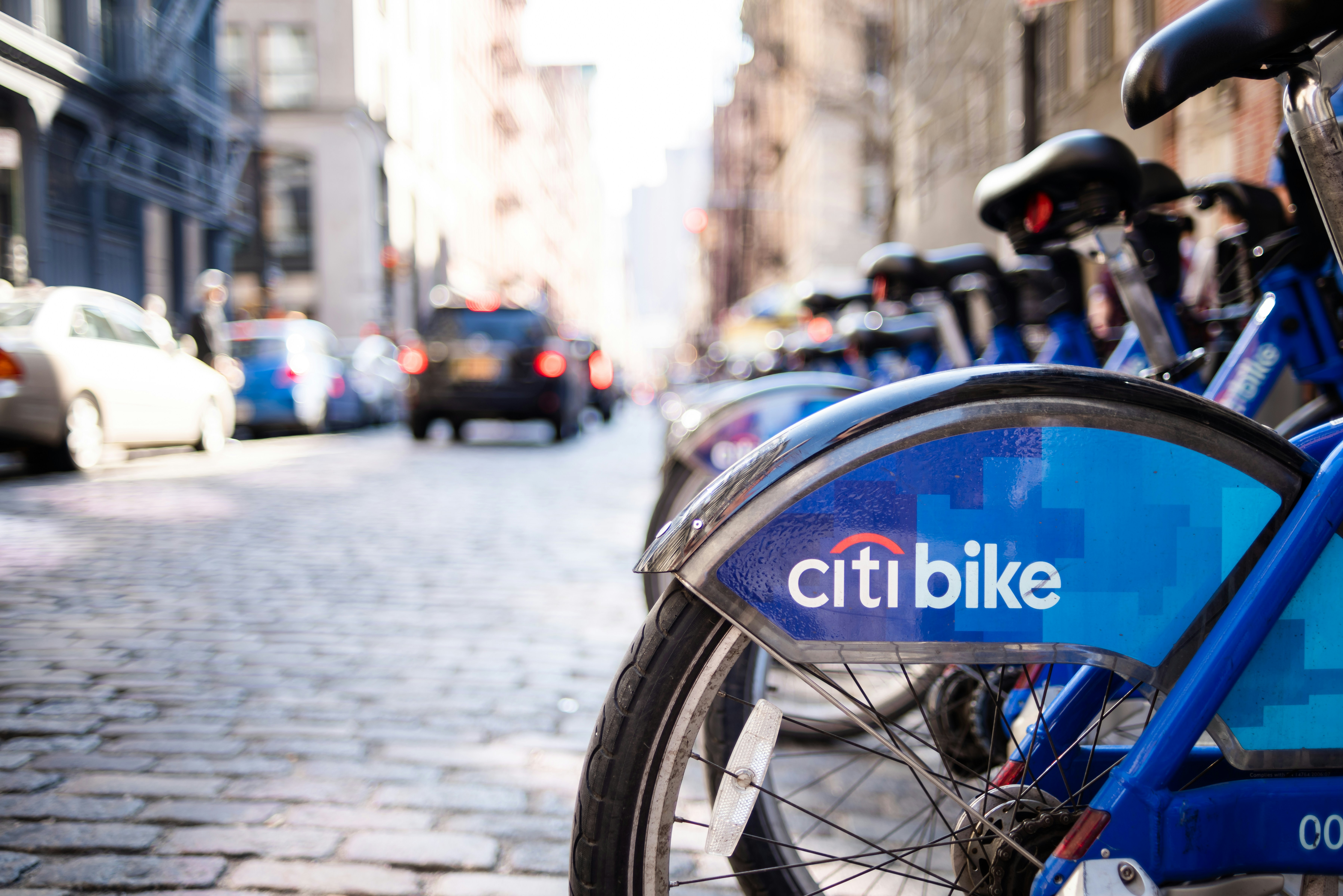 A row of bikes parked on the side of a street, 