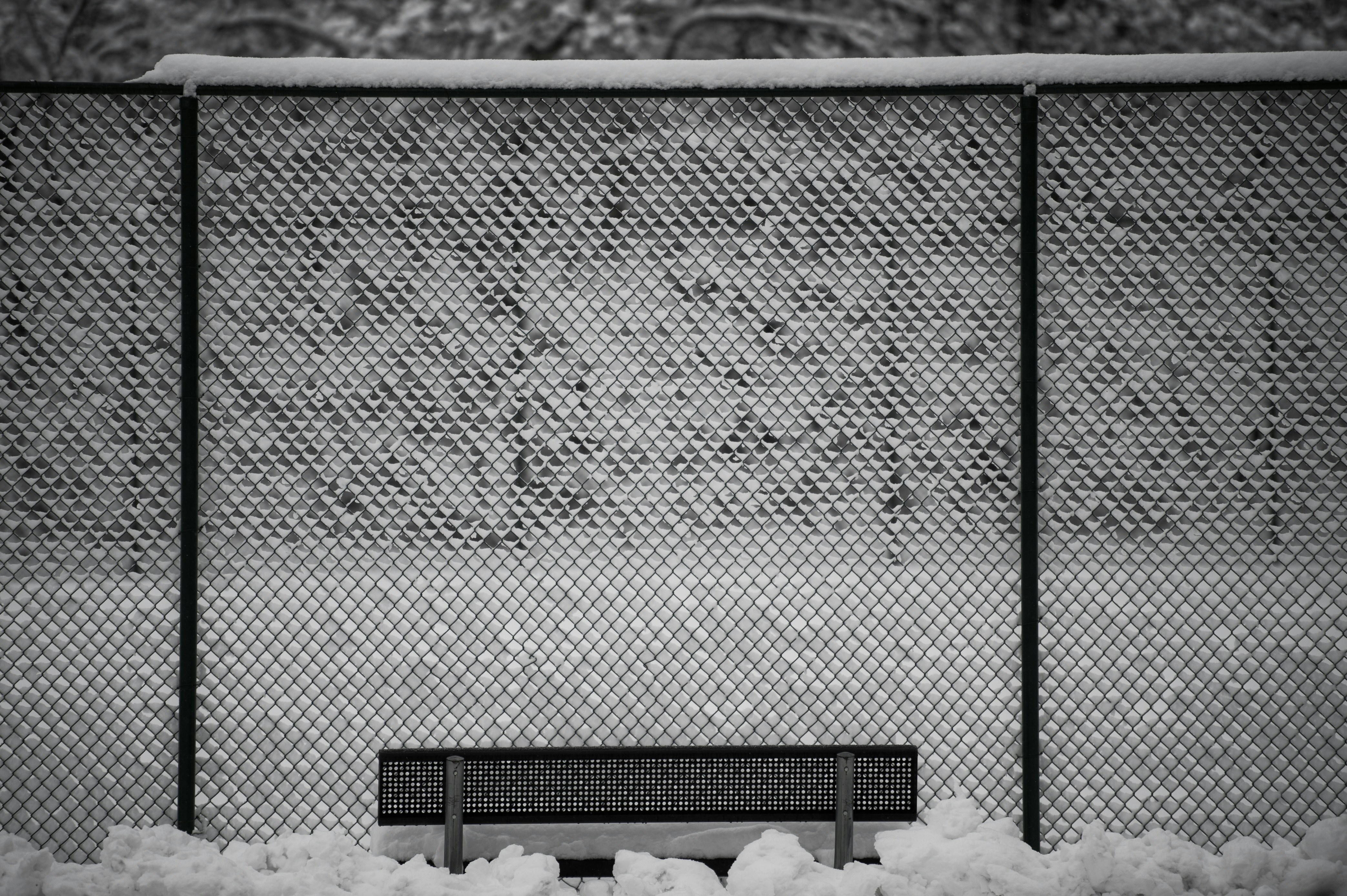 A black and white photo of a bench in the snow