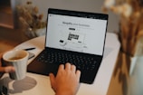 A person sitting at a table using a laptop computer