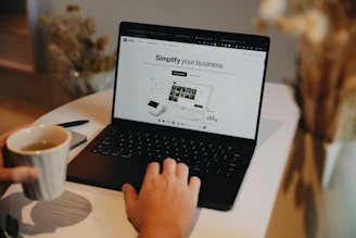 A person sitting at a table using a laptop computer
