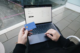 A person sitting in a chair with a laptop and a credit card